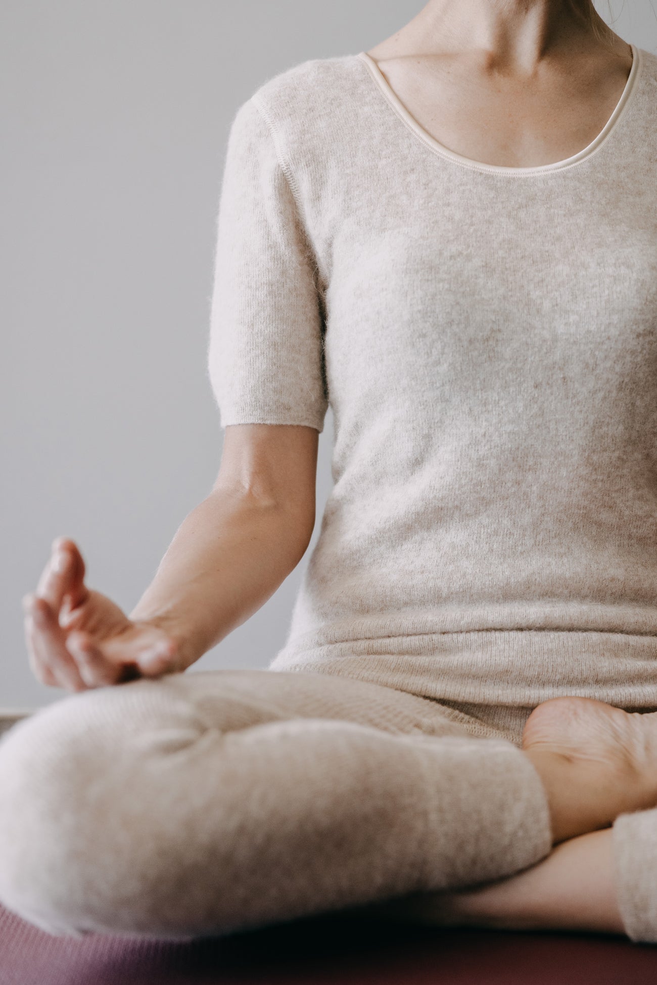 Person in Meditationspose trägt das ALPAKA Damen Shirt AMALYA, beige, weich, ohne Seitennähte, sorgt für Wärme und Komfort durch Alpakafaser-Thermoeigenschaften.