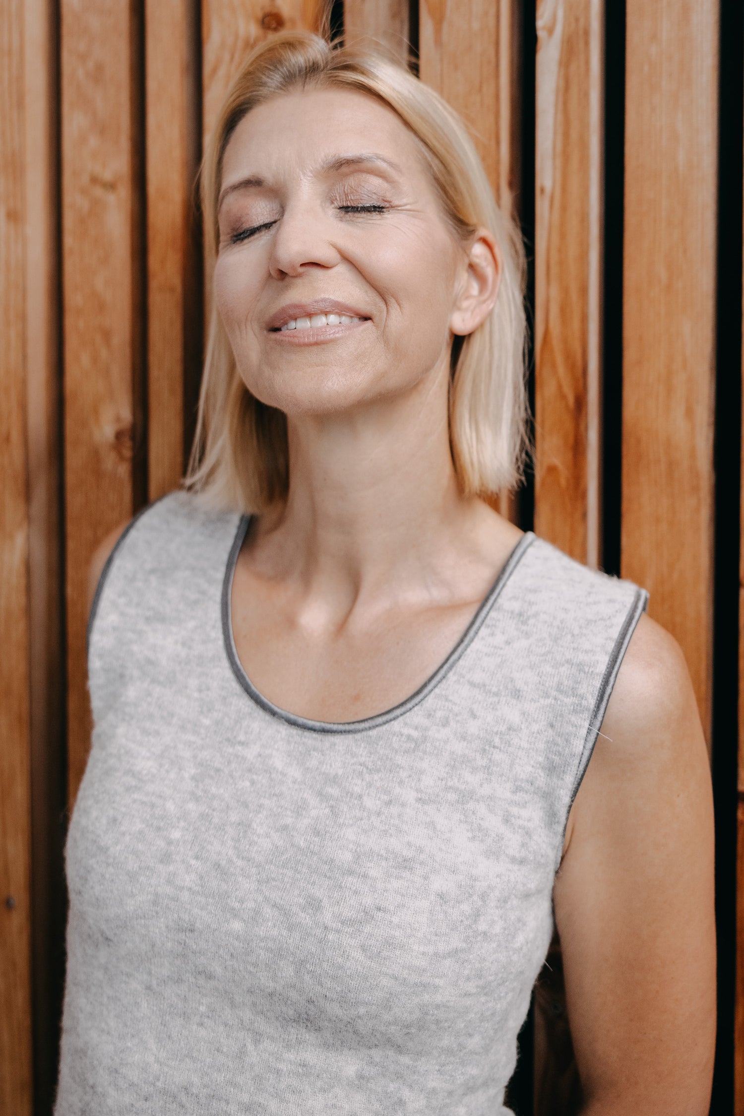 Frau genießt Ruhe im ALPAKA Damen Top AYDA, ein ärmelloses, saumfrei gestricktes Oberteil aus weicher Alpakafaser, ideal für angenehme Wärme und Komfort.