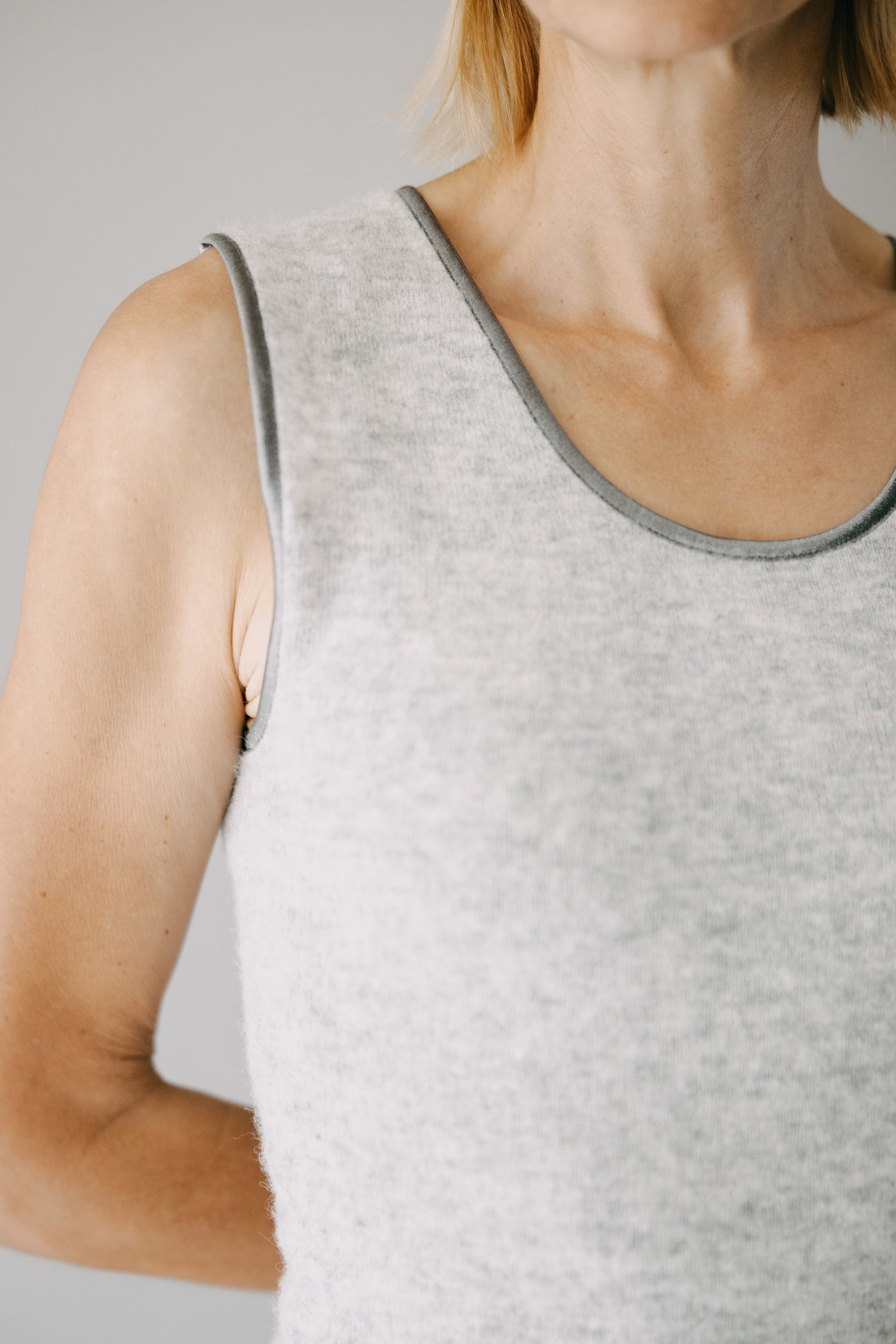 Person trägt ein ärmelloses, hellgraues ALPAKA Damen Top AYDA mit dunkleren Abschlüssen. Das Shirt ist weich und nahtlos für hohen Tragekomfort.