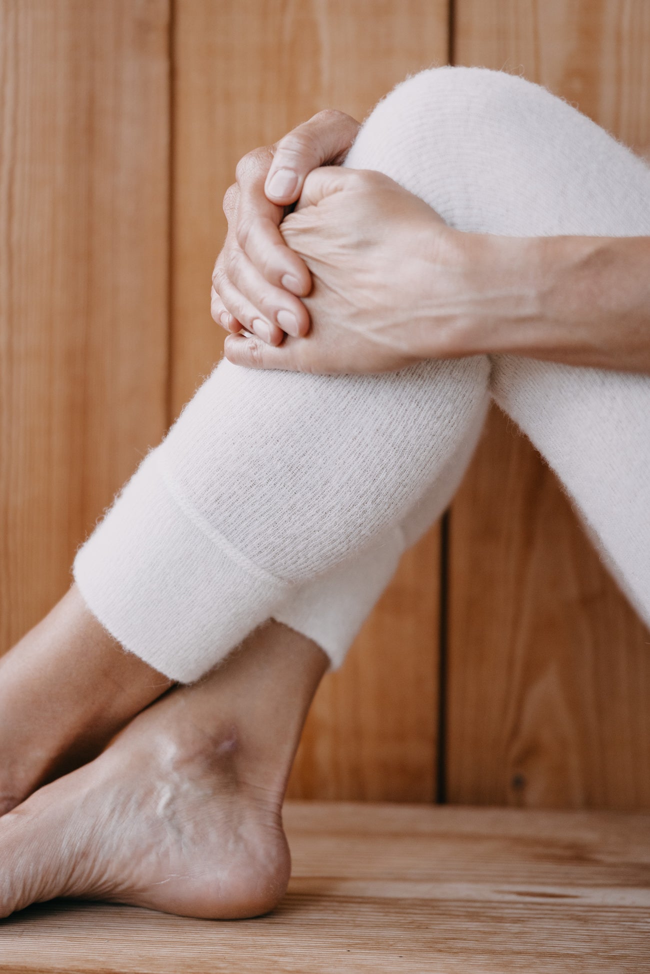 ALPAKA Damen Leggins ALBERTA an einem Bein getragen, zeigen weiches, weißes Strickmaterial von der Mitte des Schienbeins bis zum Knie, betonen Komfort und Wärme.