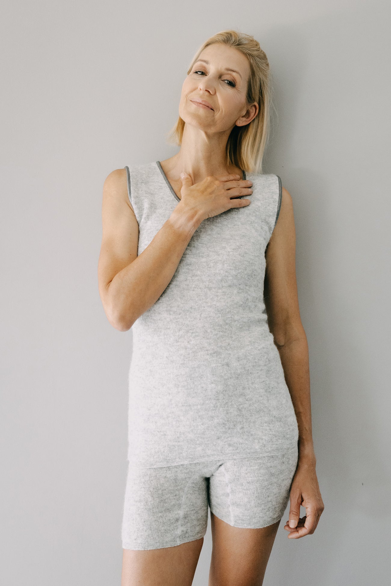 Frau in grauem Strickoutfit präsentiert ALPAKA Damen Panty AMARU, bekannt für weiche Alpakafaser, optimalen Tragekomfort und elegante Optik.