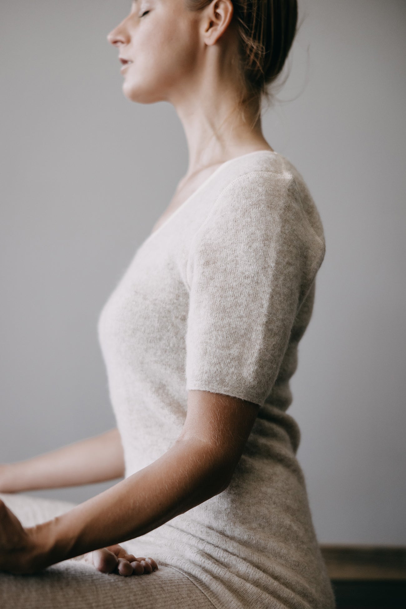 Frau im Profil in meditativer Pose, trägt das ALPAKA Damen Shirt AMALYA, kurzärmelig, ohne Seitennähte, bietet Weichheit und hohen Tragekomfort.