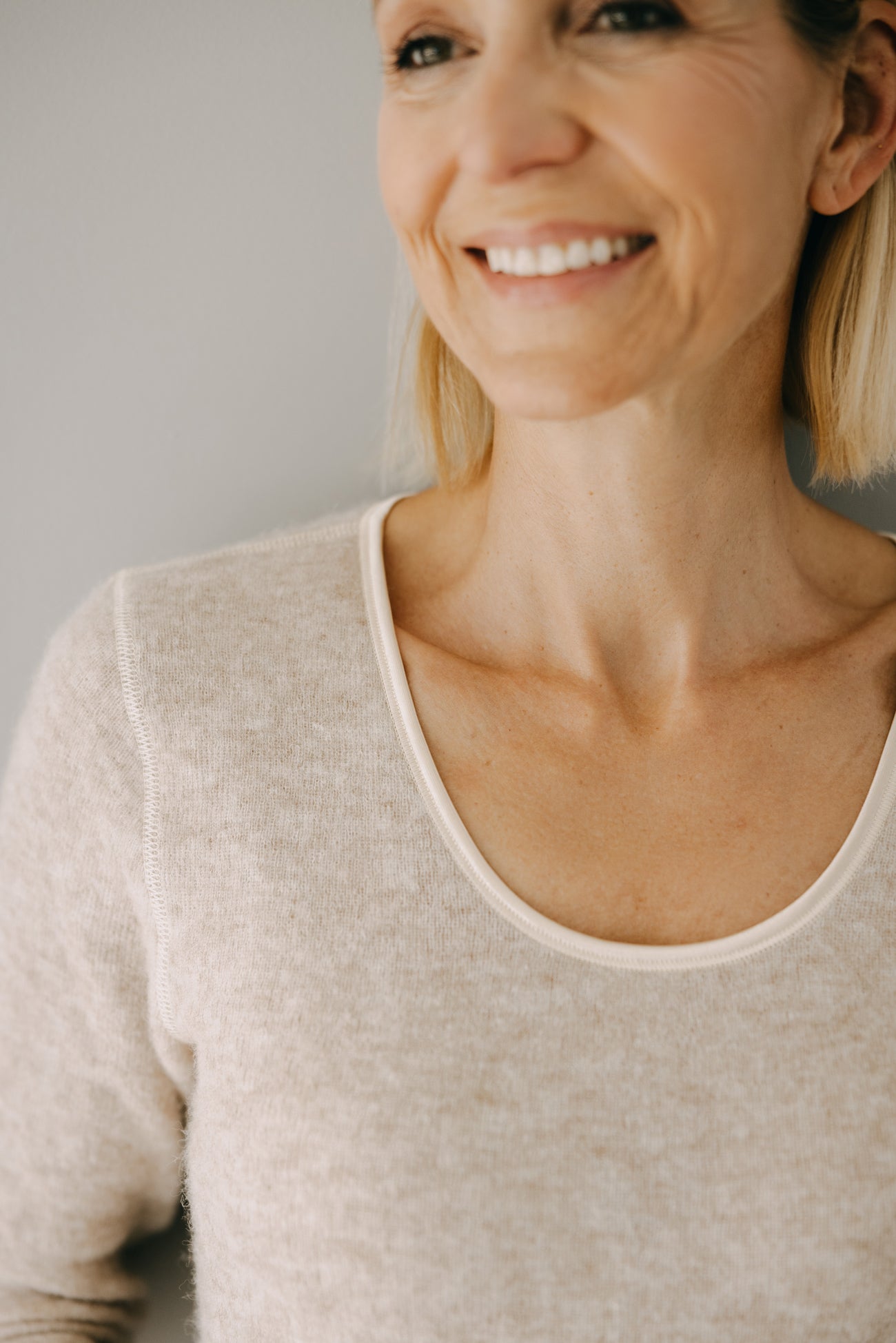 Nahaufnahme eines lächelnden Gesichts mit sichtbarem ALPAKA Damen langarm Shirt AVELYNA. Weiches, nahtloses Design mit Rundhalsausschnitt, ideal für Komfort und Wärme.